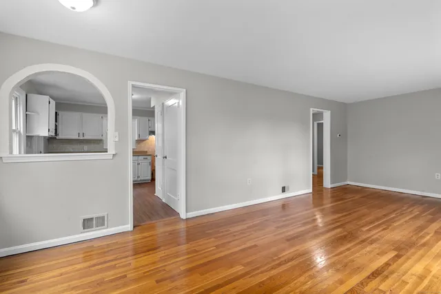 a view of hallway with window and wooden floor