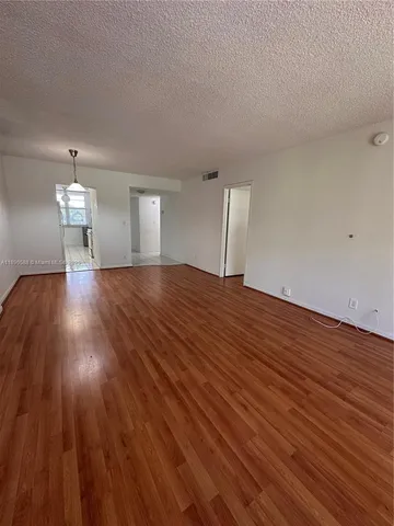 a view of an empty room with wooden floor and stairs