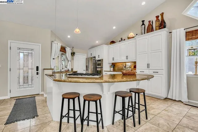 a kitchen with stainless steel appliances granite countertop a table chairs sink and cabinets