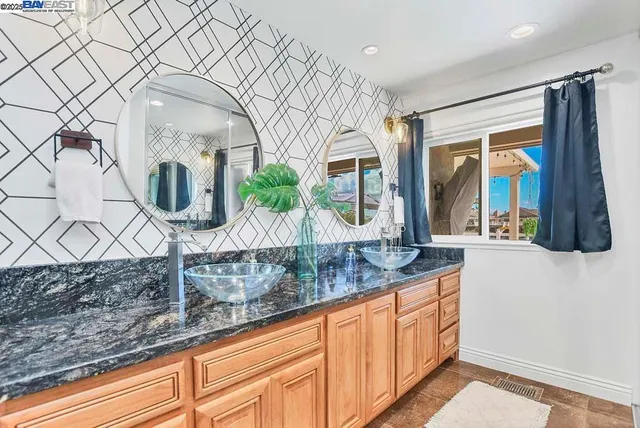 a bathroom with a granite countertop sink and a mirror