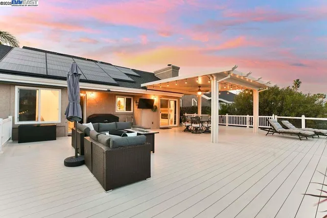 a view of a patio with couches table and chairs with wooden floor and fence
