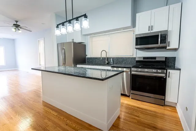 a kitchen with granite countertop a stove top oven and refrigerator