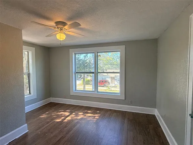a view of an empty room with wooden floor and window