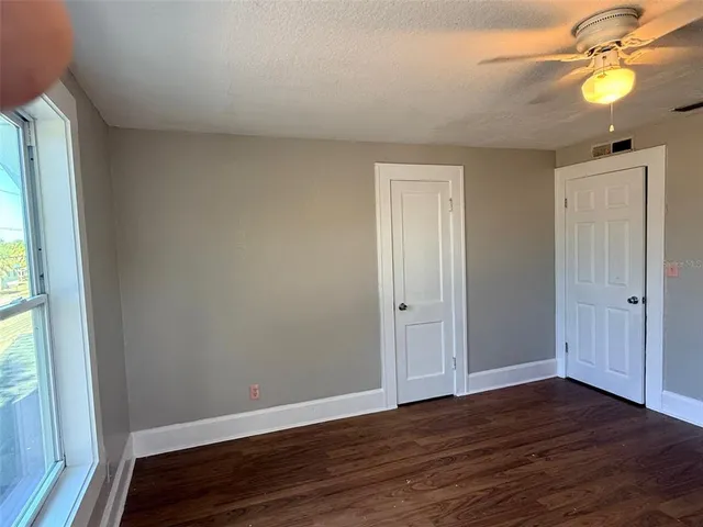 a view of an empty room with wooden floor and a window