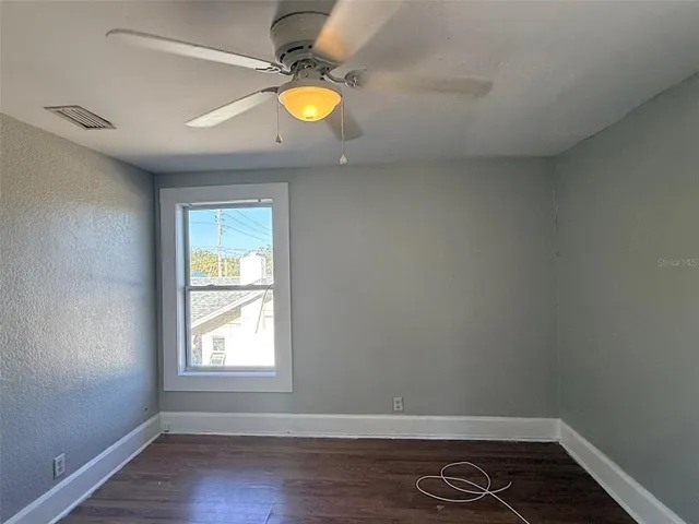 an empty room with wooden floor and window