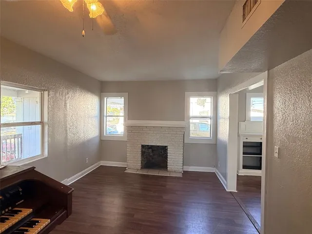 an empty room with windows fireplace and wooden floor