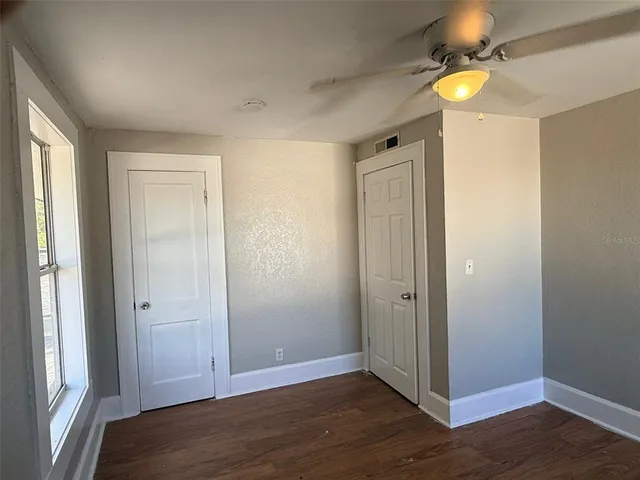 an empty room with wooden floor and fan