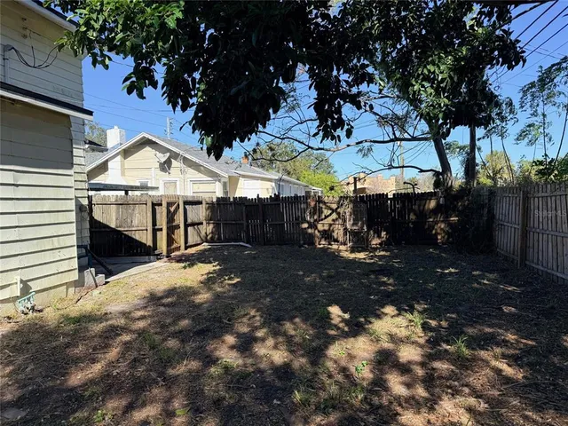 a view of a house with a yard tree and wooden fence