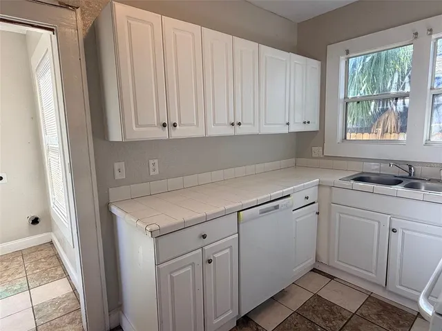 a kitchen with white cabinets and sink