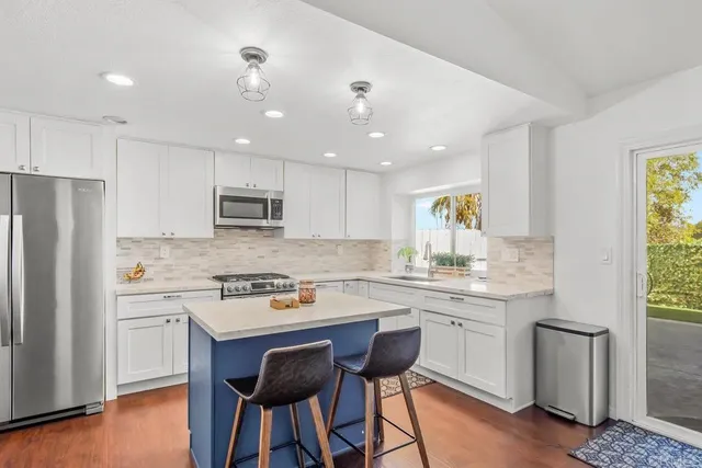 a kitchen with a sink a stove a refrigerator cabinets and a dining table