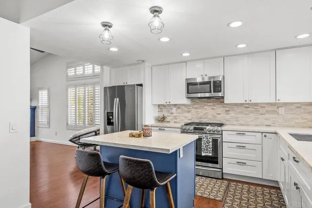 a kitchen with kitchen island granite countertop a sink a center island stainless steel appliances and cabinets