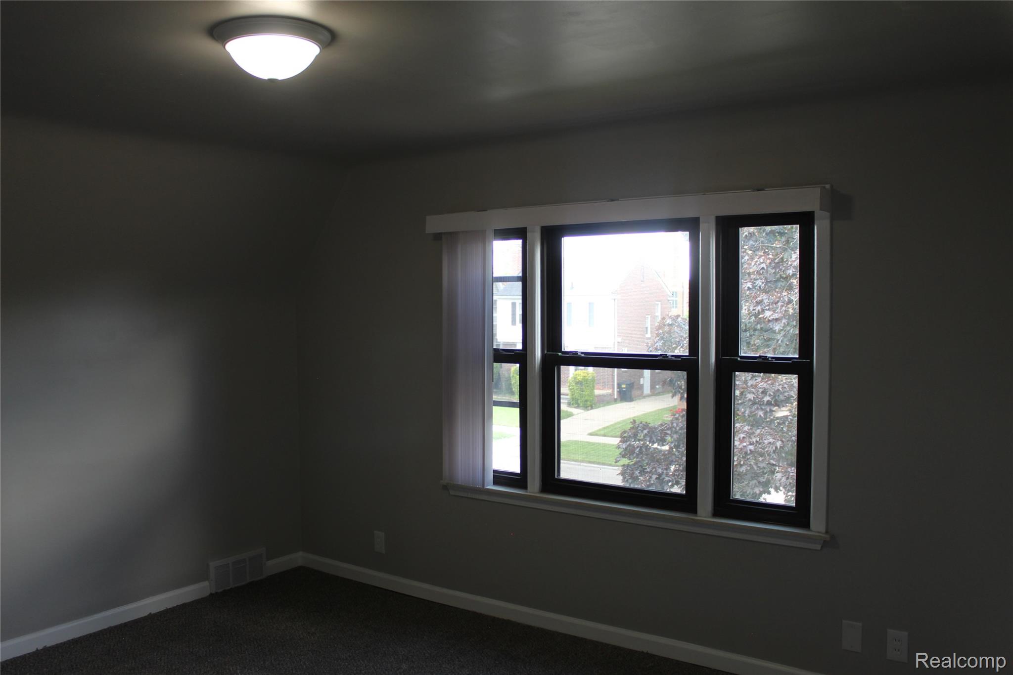 5543 Balfour Road Detroit, MI 48224 - Photo 50 of 54 Interior room featuring a large window with black framing and white trim, neutral gray wall paint, and dark carpeting
