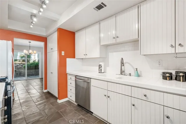 a kitchen with a sink dishwasher and white cabinets