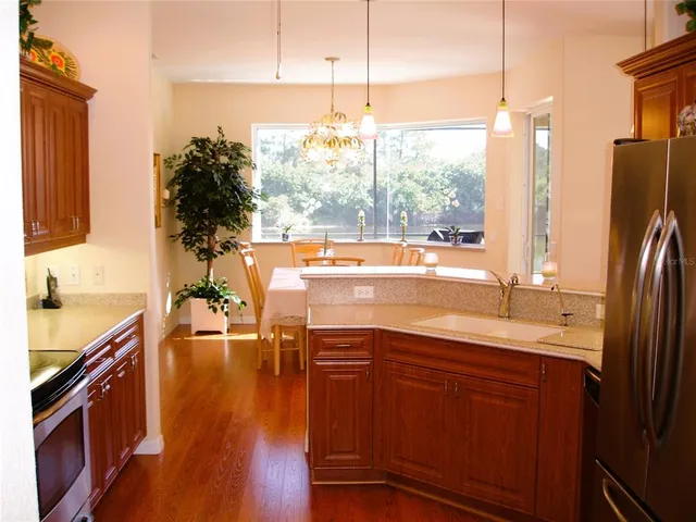 a kitchen with stainless steel appliances granite countertop a sink a stove and a wooden floor