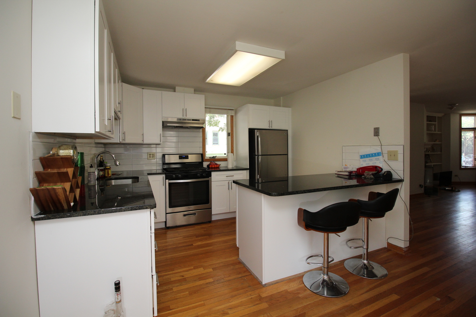 Undisclosed Address Chicago, IL 60657 - Photo 4 of 23 a kitchen with stainless steel appliances kitchen island granite countertop a refrigerator a stove a sink a counter space and cabinets