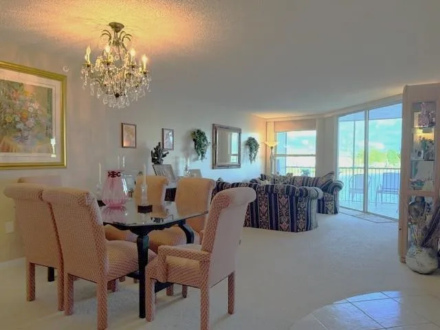 a view of a dining room with furniture a chandelier and large windows