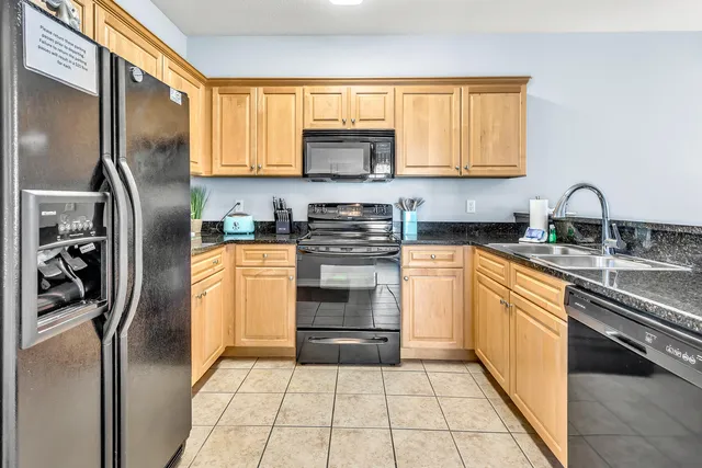 a kitchen with stainless steel appliances granite countertop a stove a sink and a refrigerator