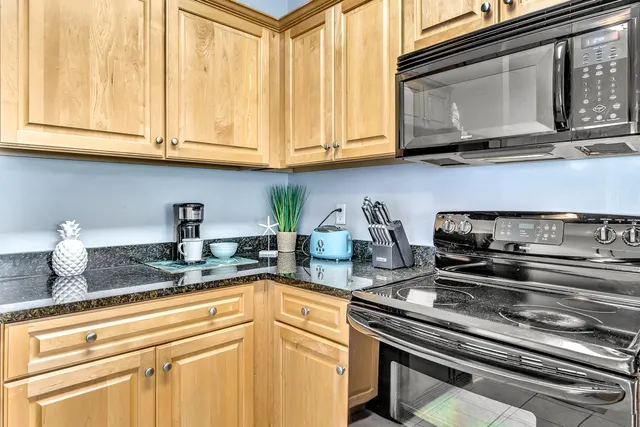 a kitchen with stainless steel appliances granite countertop white cabinets and a stove top oven