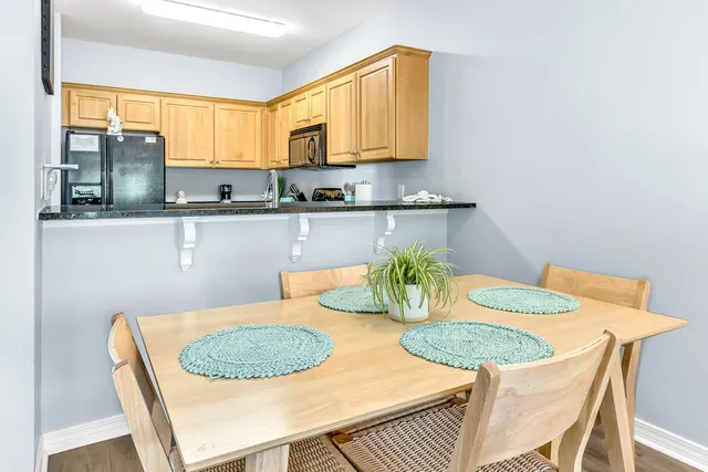a kitchen with stainless steel appliances granite countertop a table chairs and a microwave