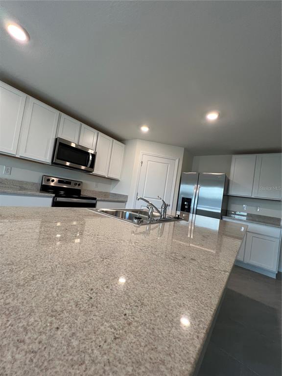8884 Southwest 49th Circle Ocala, FL 34476 - Photo 36 of 39 a kitchen with stainless steel appliances granite countertop a sink a stove and a refrigerator with wooden floor