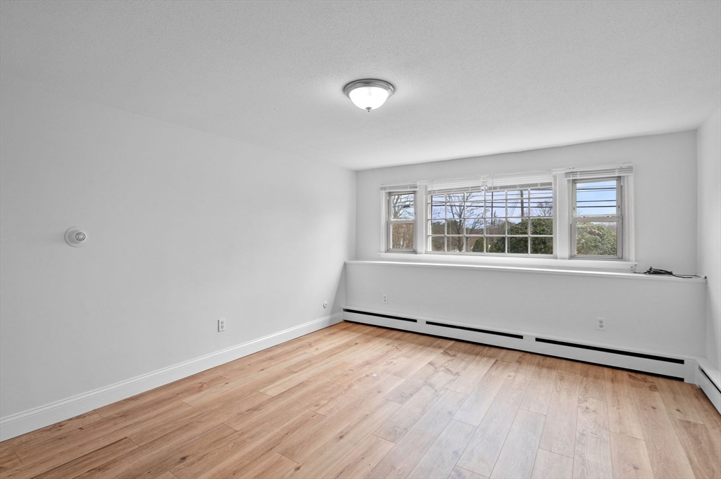 121 Cambridge Road, Unit 2 Woburn, MA 01801 - Photo 6 of 23 an empty room with wooden floor and windows
