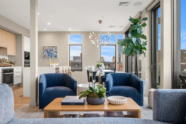 a living room with furniture potted plant and kitchen view