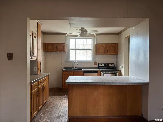 a kitchen with stainless steel appliances granite countertop a refrigerator a sink dishwasher a stove and a dining table with wooden floor