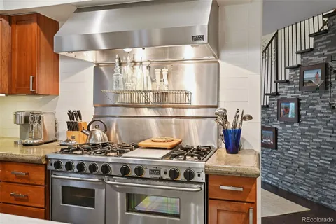 a kitchen with a stove a sink dishwasher a dining table and chairs with wooden floor