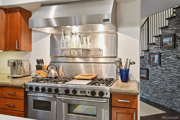 a kitchen with a stove a sink dishwasher a dining table and chairs with wooden floor