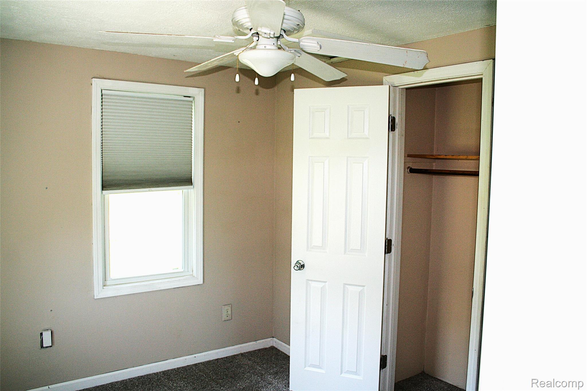 2199 Sandy Creek Road Monroe, MI 48162 - Photo 9 of 13 Unfurnished bedroom featuring ceiling fan and dark carpet
