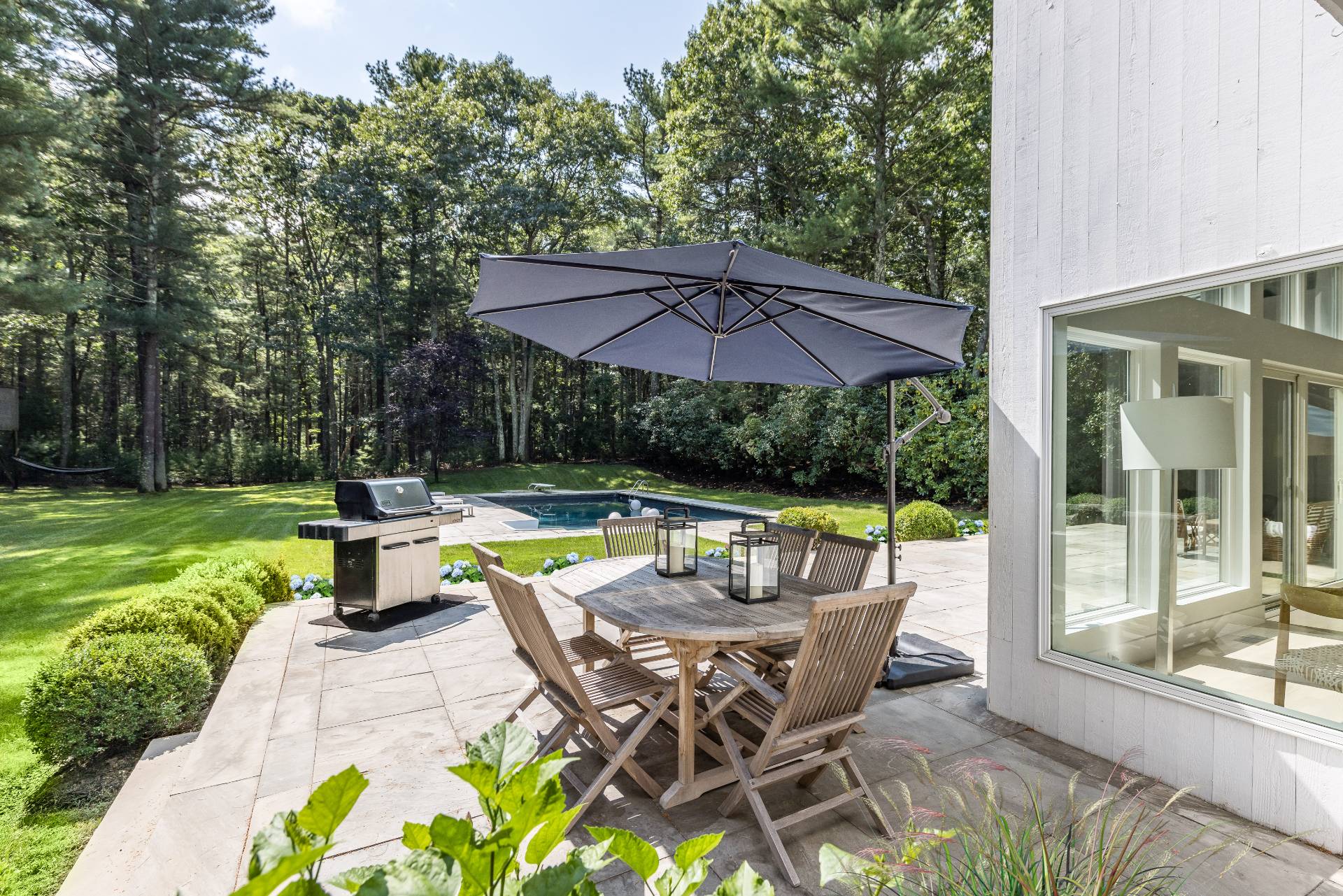 52 Bull Path East Hampton, NY 11937 - Photo 20 of 24 a view of backyard with swimming pool and table and chairs under an umbrella