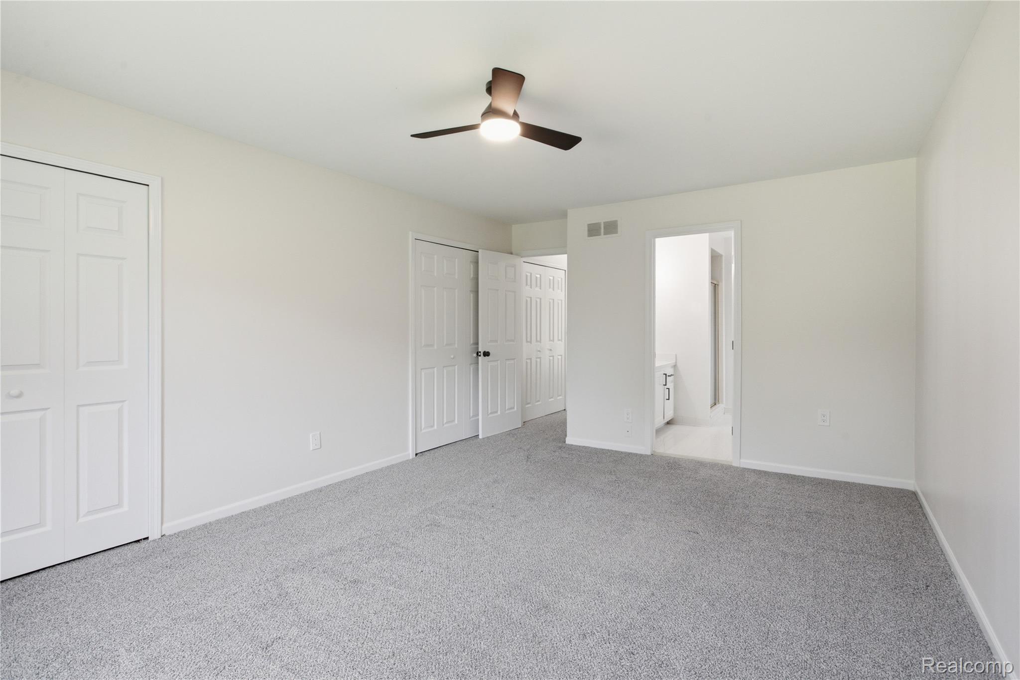 52658 Stag Ridge Drive Macomb, MI 48042 - Photo 19 of 28 Spacious room featuring light grey carpeting, white walls, a ceiling fan with integrated lighting, and multiple panel doors