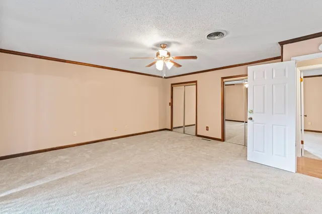 an empty room with chandelier fan and windows