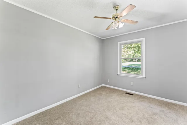 an empty room with a window and a fan