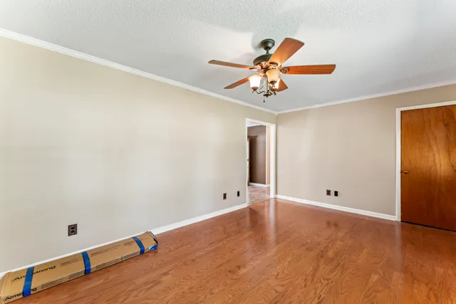 a view of an empty room with window and wooden floor