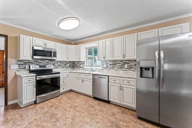 a kitchen with white cabinets stainless steel appliances and a window