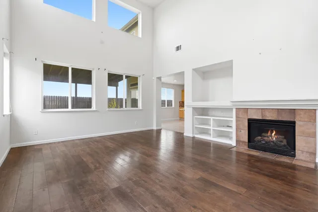 a view of an empty room with wooden floor fireplace and a window