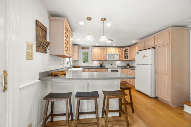 a kitchen with kitchen island a stove a refrigerator and a dining table with wooden floor