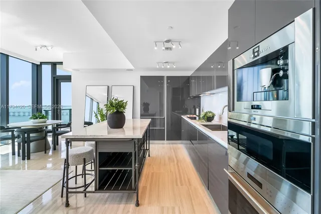 a kitchen with stainless steel appliances kitchen island granite countertop a stove a sink dishwasher and white cabinets with wooden floor