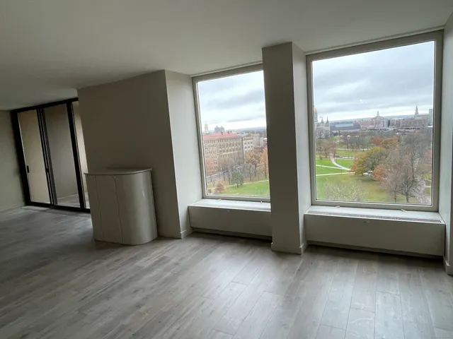 a view of an empty room with wooden floor and a window