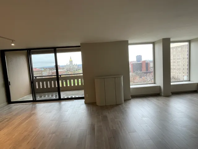 a view of an empty room with wooden floor and a window
