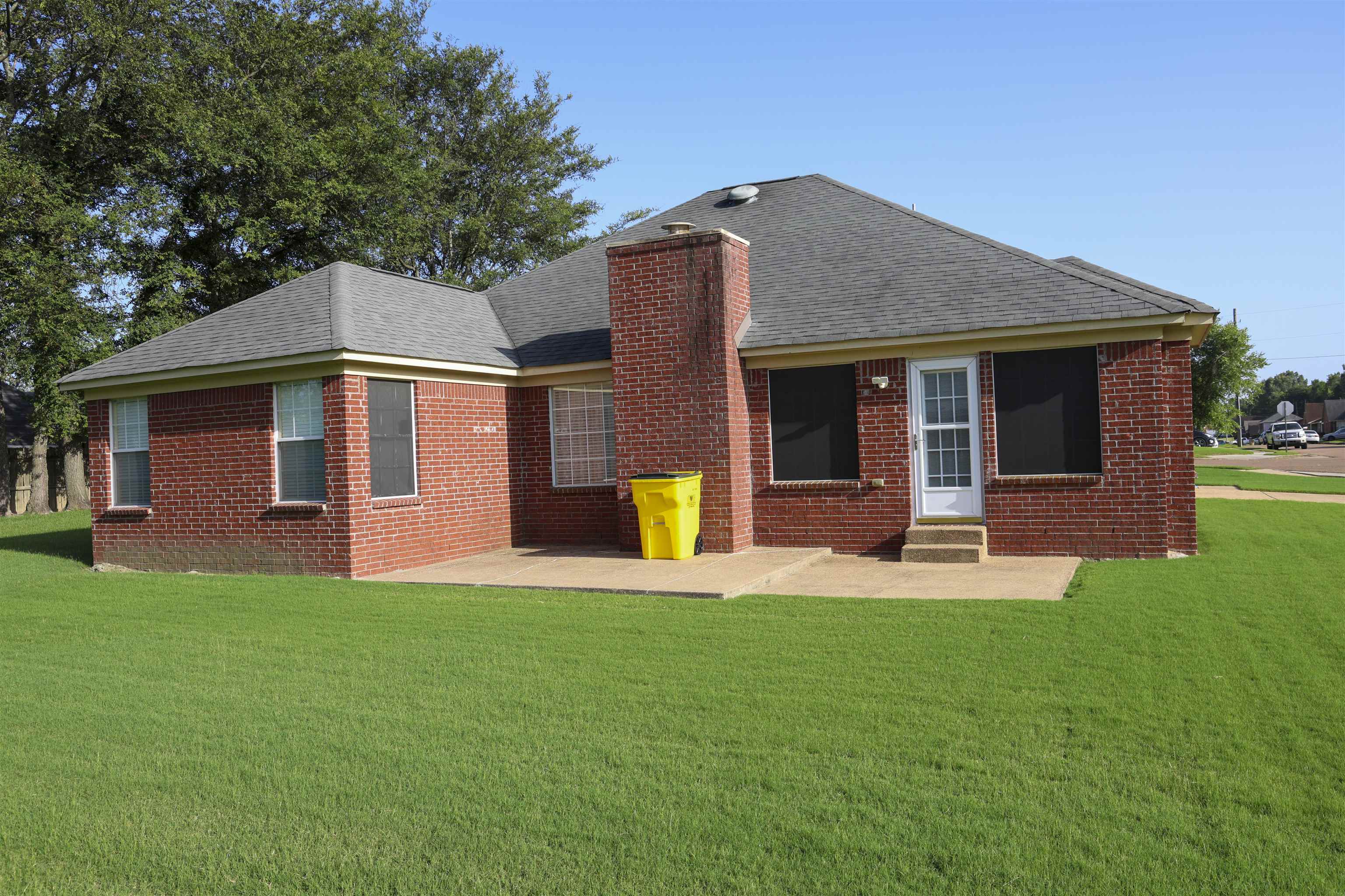 6626 Finch Road Memphis, TN 38141 - Photo 3 of 14 Brick exterior featuring a gabled roofline, a rear patio, and a chimney