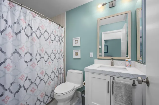 a bathroom with a granite countertop sink mirror vanity and toilet