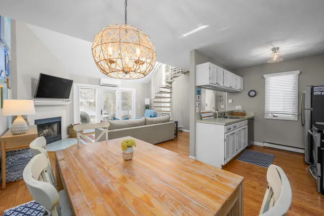 a kitchen with a refrigerator a stove a sink dishwasher a dining table and chairs with wooden floor