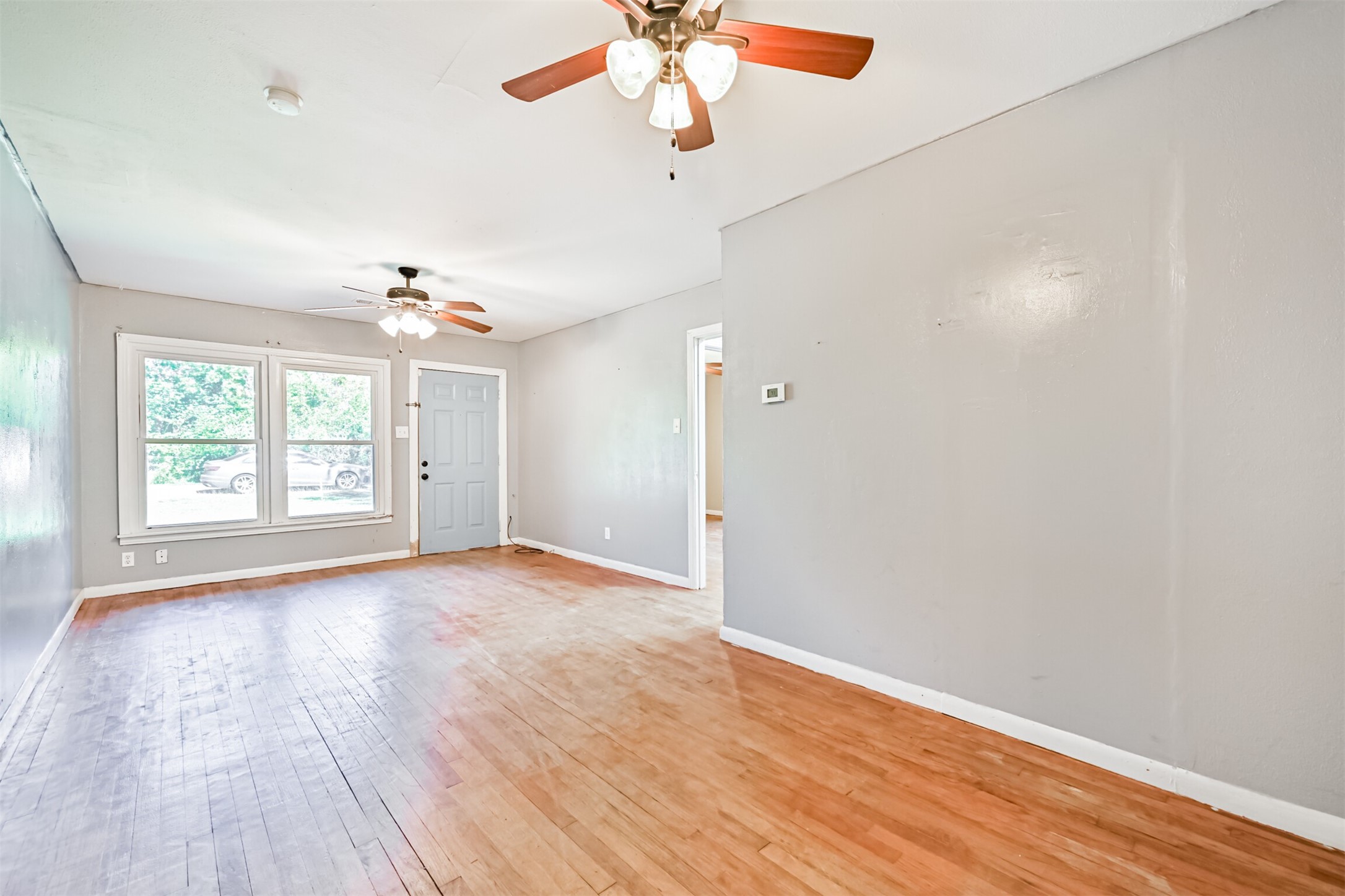 1007 Plum Street La Marque, TX 77568 - Photo 4 of 16 an empty room with wooden floor chandelier fan and windows