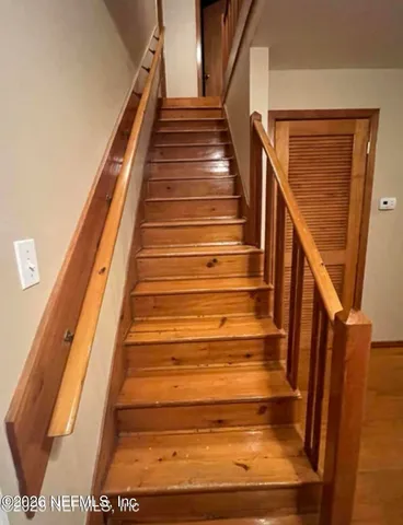 a view of an empty room with window and wooden floor