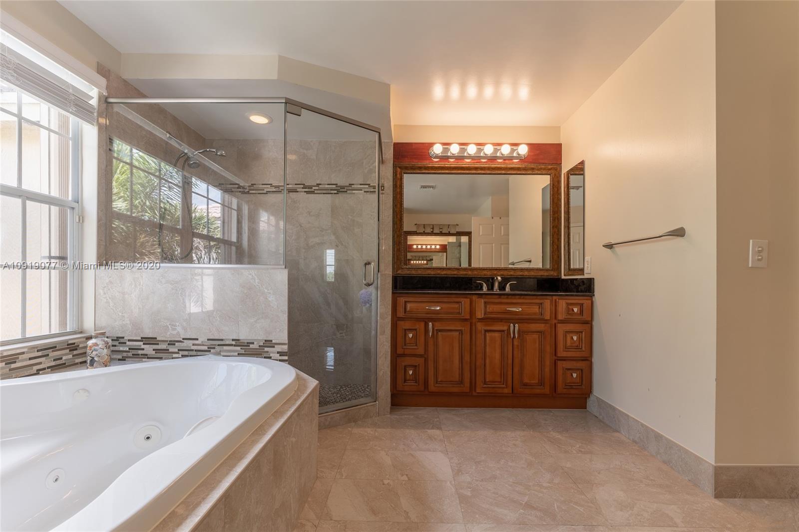 12358 St Simon Drive Boca Raton, FL 33428 - Photo 37 of 89 a bathroom with a tub a sink and a large mirror