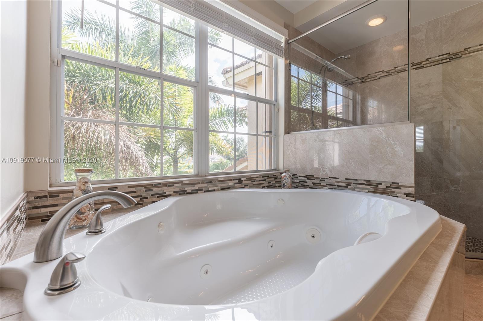12358 St Simon Drive Boca Raton, FL 33428 - Photo 38 of 89 a bathroom with a tub a large window and a shower