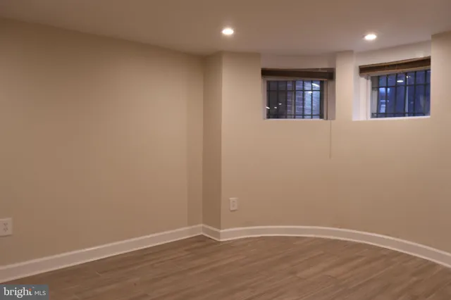 a view of an empty room with wooden floor and window
