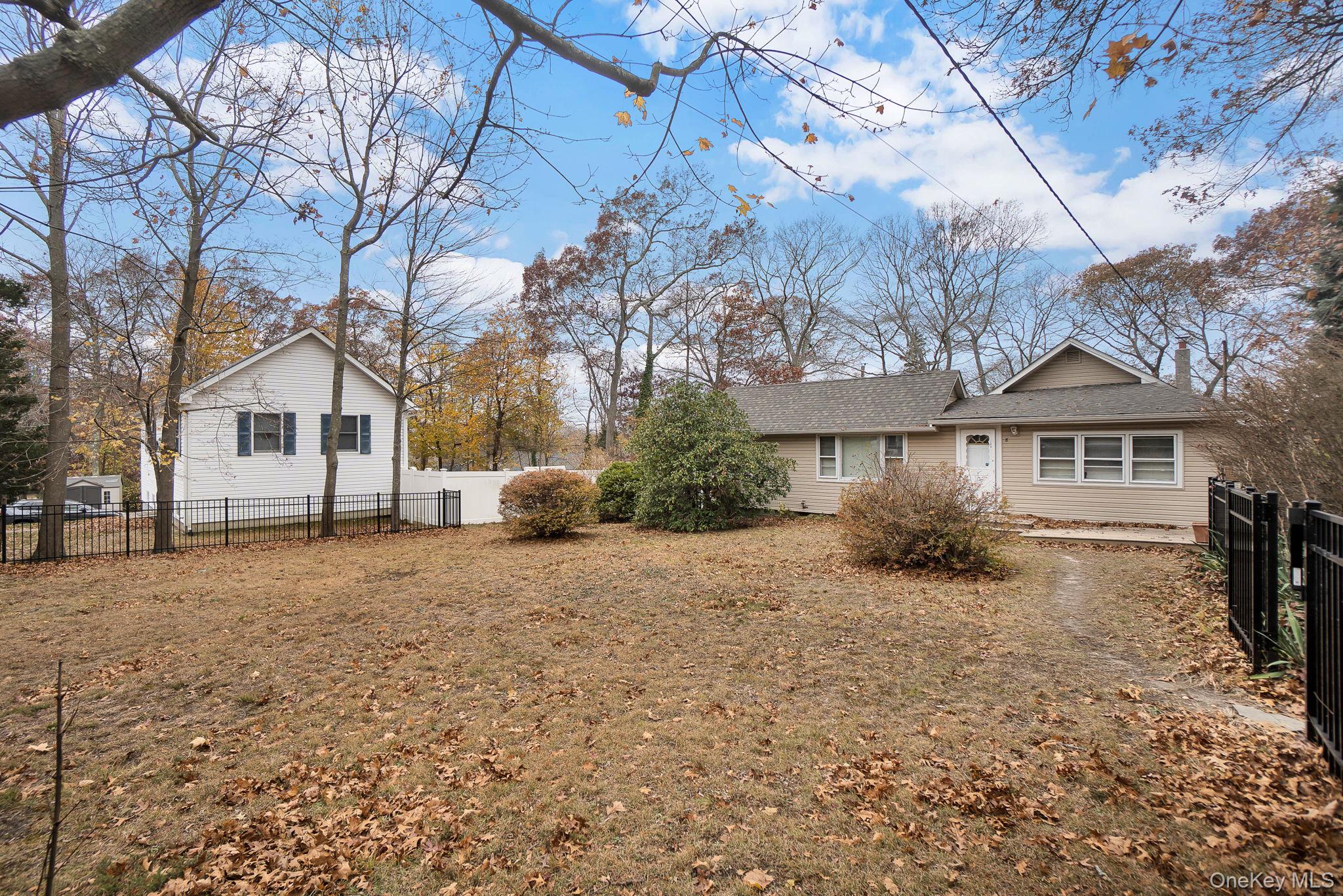 8 Evergreen Road Rocky Point, NY 11778 - Photo 1 of 20 a front view of a house with a dirt yard and a large tree